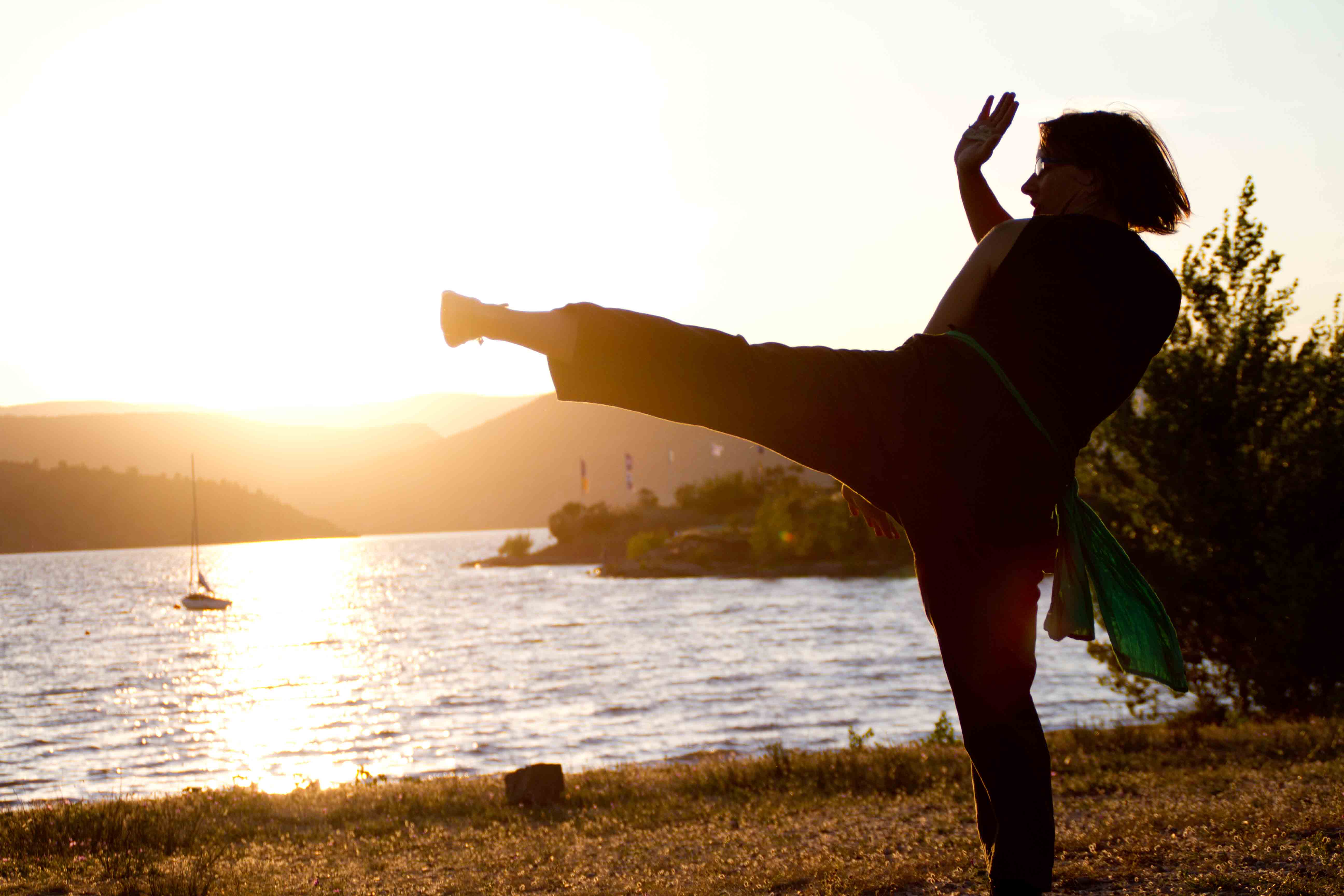 Femme donnant un coup de pied latéral, au coucher du soleil face à un lac